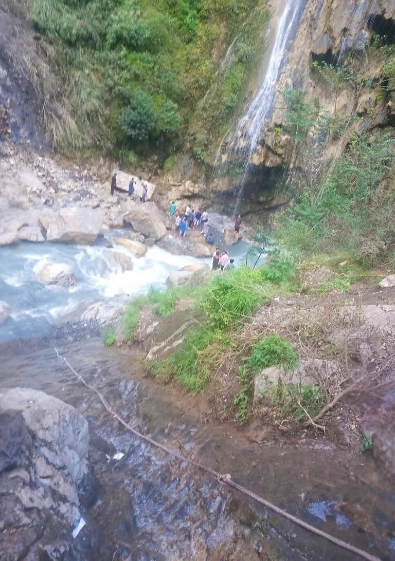 Umbrella waterfall in a valley with people standing around
