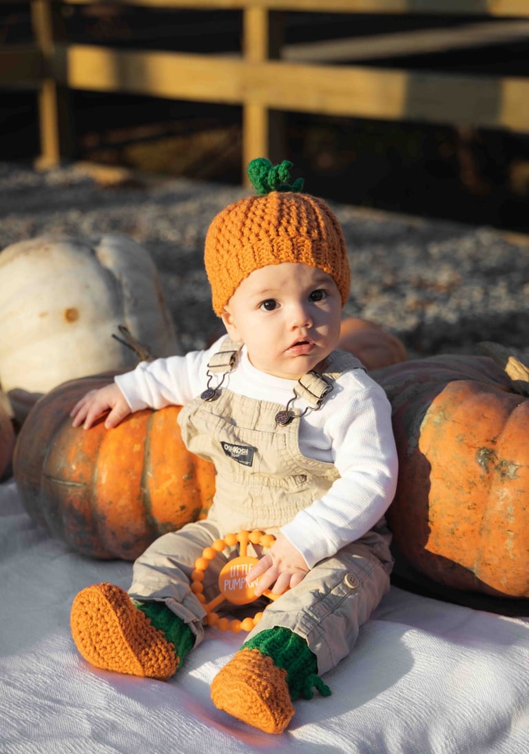 Super cute photo of baby boy in a pumpkin patch, dressed as a pumpkin.