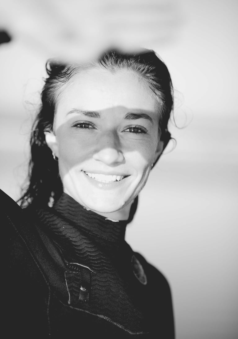 a woman in a wetsuit smiling and holding a surfboard