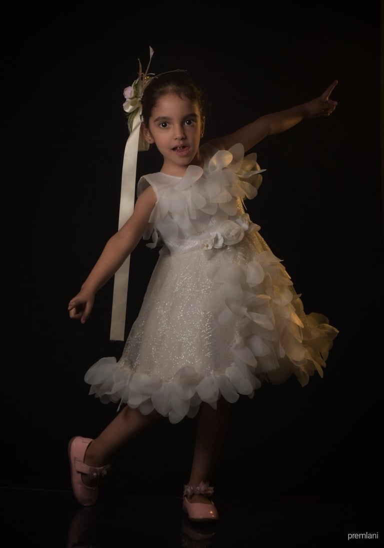 Young girl in a beautiful white flower dress striking a pose with pink shoes. Wonderpose photograph