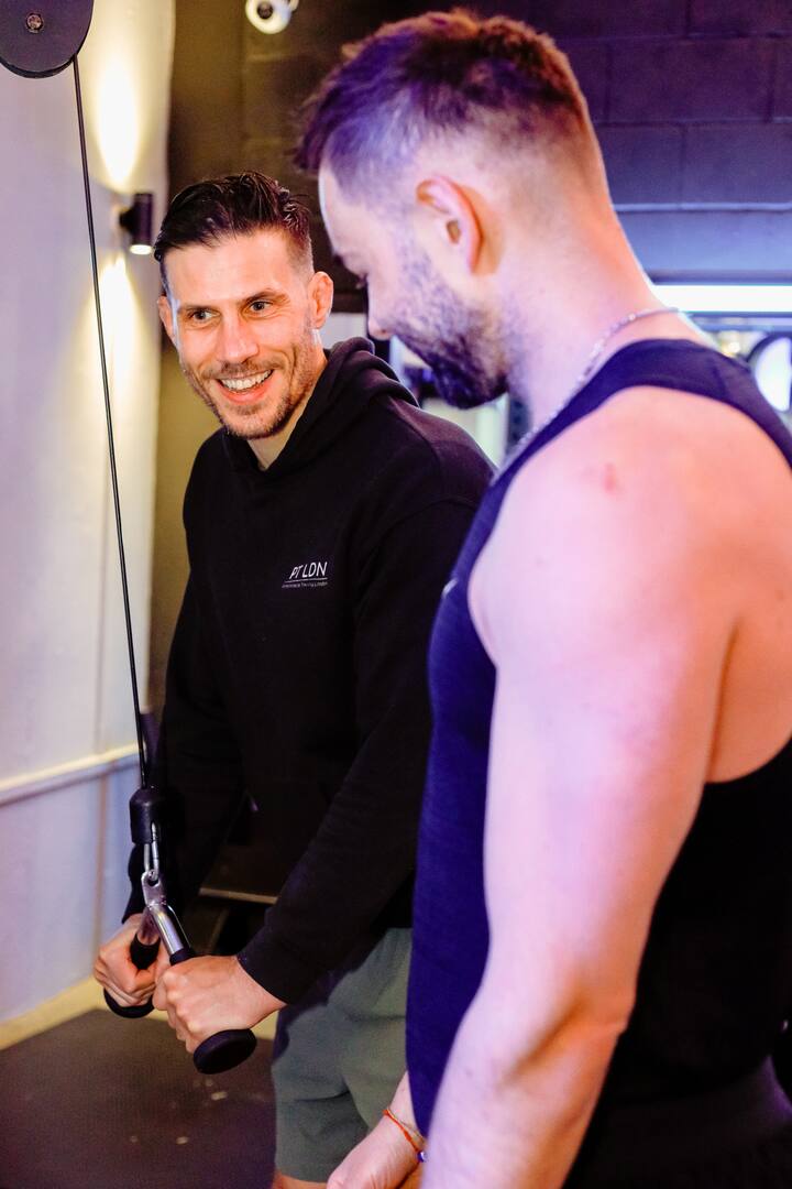 A personal trainer demonstrating an arm exercise to a client