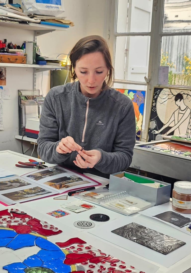 Geste artisanal d'Édith Théret assemblant avec précision des pièces de verre pour un vitrail.