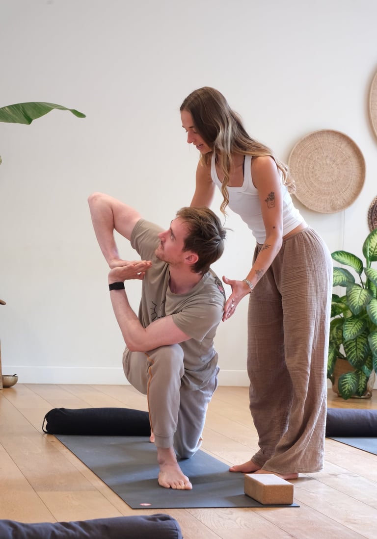 Jean adjusting a student in a yoga pose  in Leiden