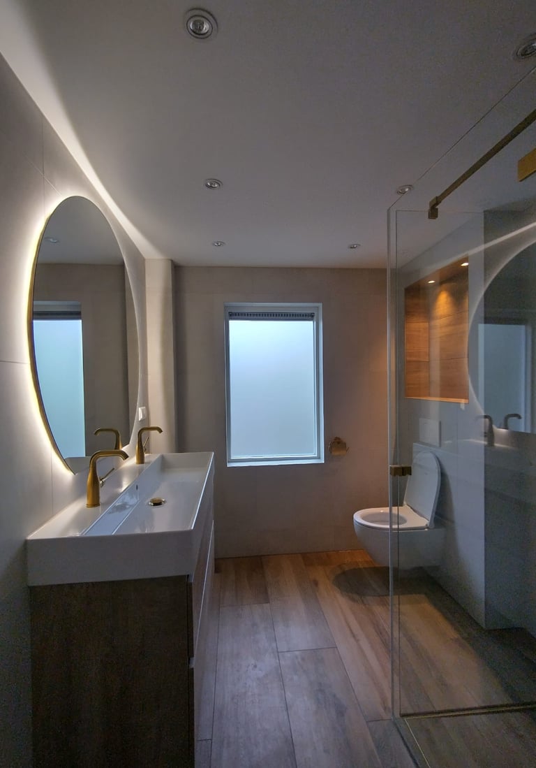 Moderne badkamer met een dubbele wasbak, gouden kranen en een inloopdouche.