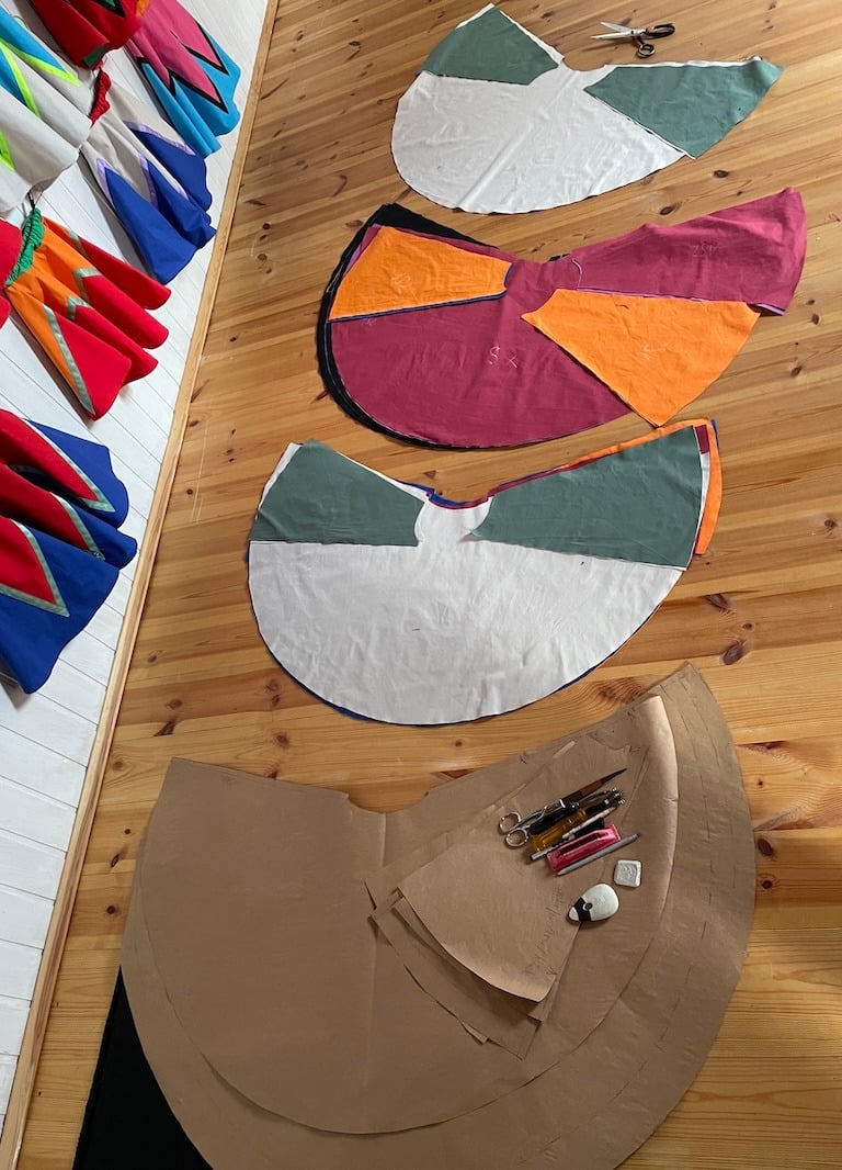 Handmade colorful fabric patterns and sewing tools laid on a wooden floor in a clothing design studio.