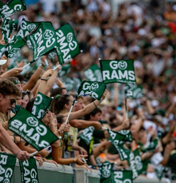 Image of several people blurred out at the stadium waving green flags that read GO RAMS.