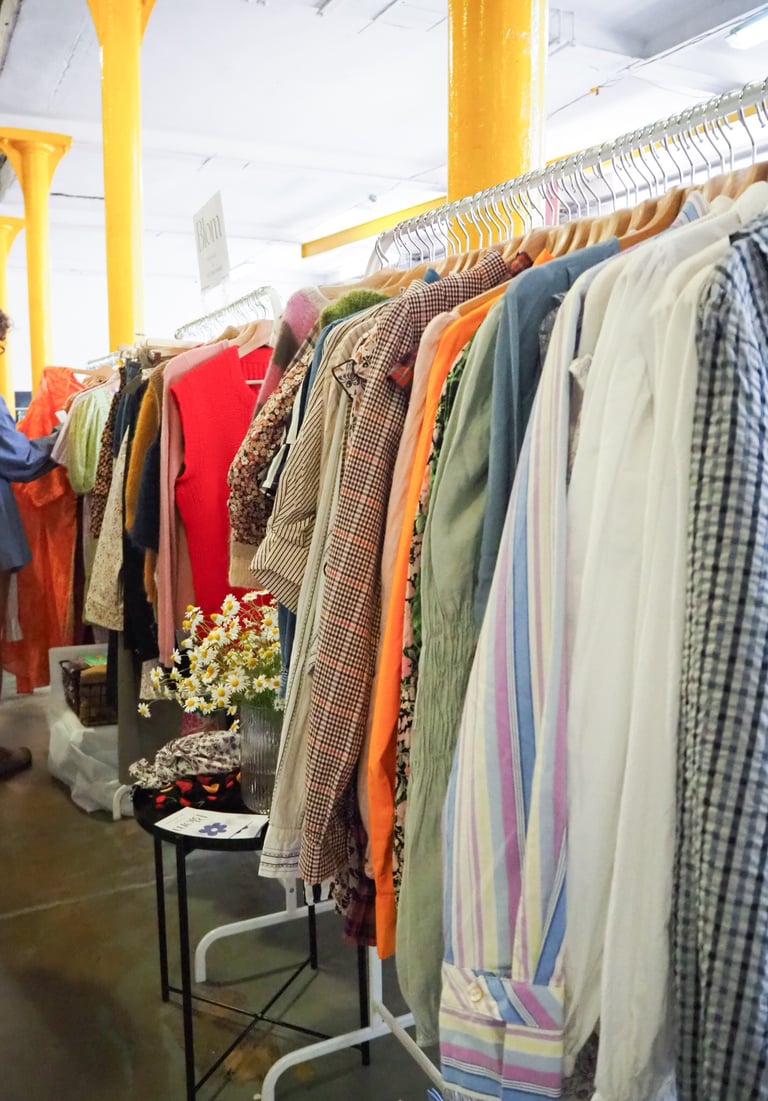 kobieta przegląda ubrania na wieszakach na targach odzieży vintage