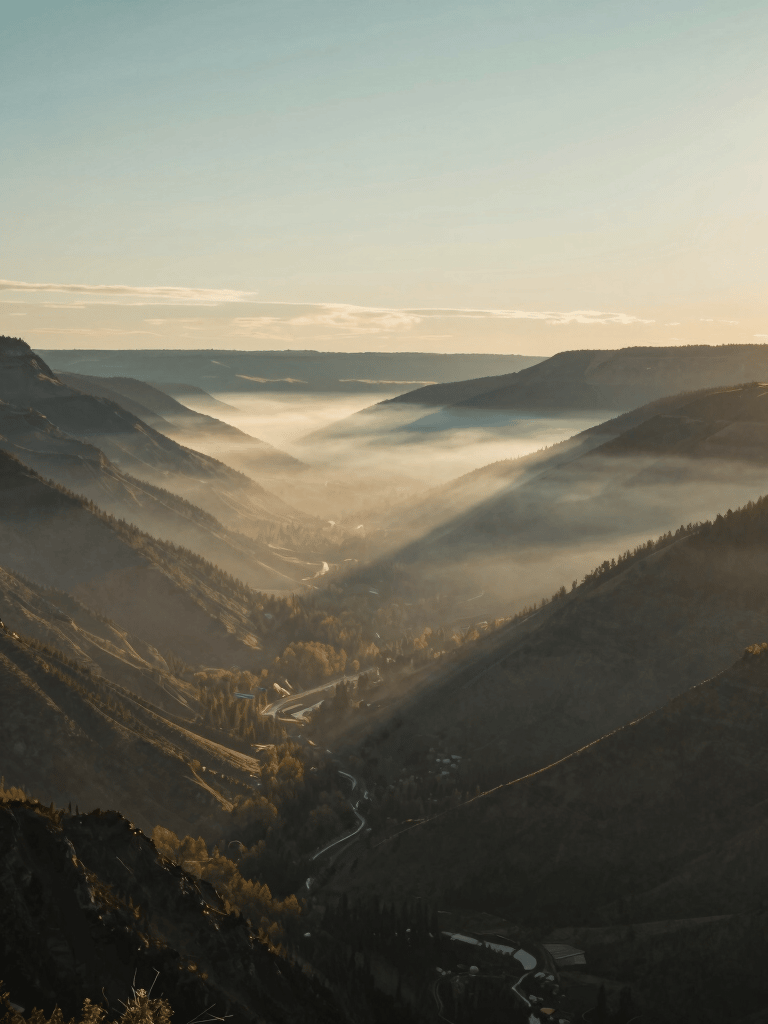 A wide-angle landscape of a misty North American / US valley at sunrise, sophisticated teal gray and muted gold tones, serene and modern photography.