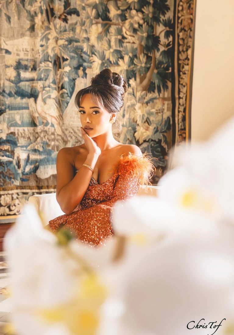 Photographie d'une femme en robe de soirée orange à paillettes posant devant une tapisserie à Valmy