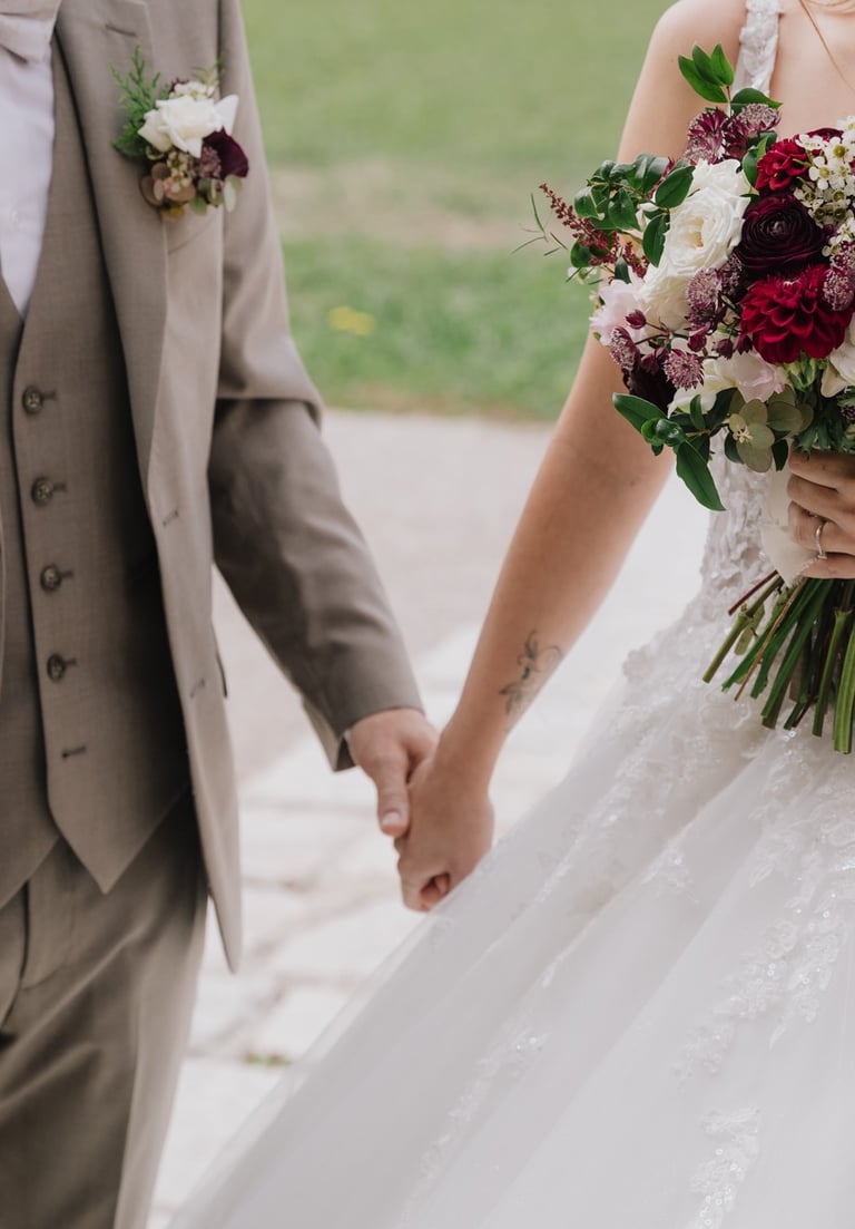 zoom sur mariés se tiennent la main et bouquet