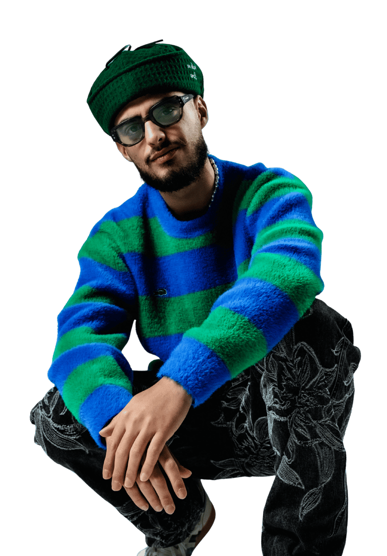 a man in a blue and green sweater and black pants