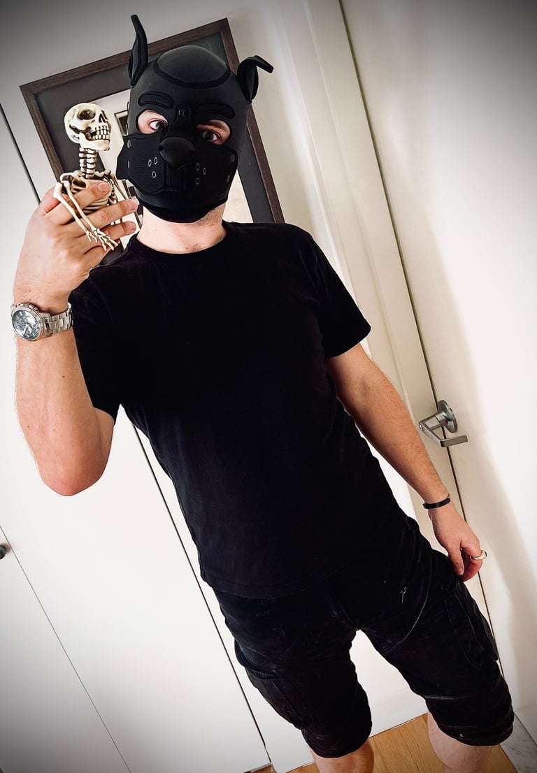 Man posing in a pup mask with a toy skeleton.