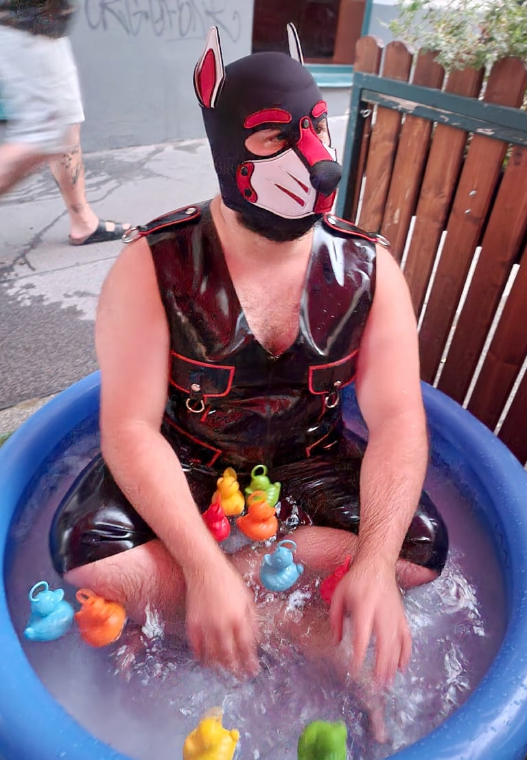 A man playing in a kiddie pool wearing a pup mask.