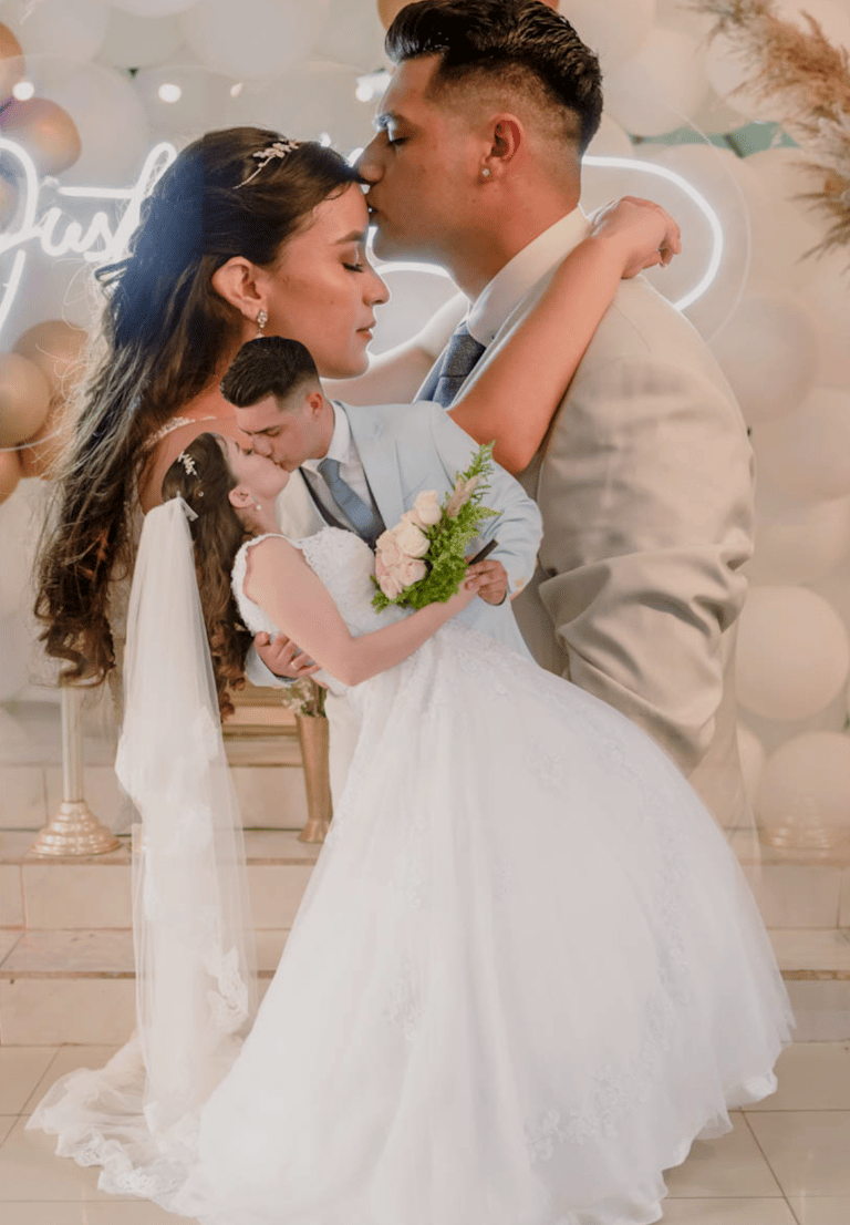 a bride and groom kissing in front of a neon sign