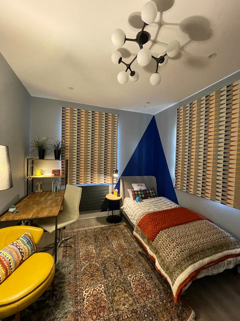 Teen bedroom with single bed, colour block, Harlequin blind, accent chair, study table, storage, rug