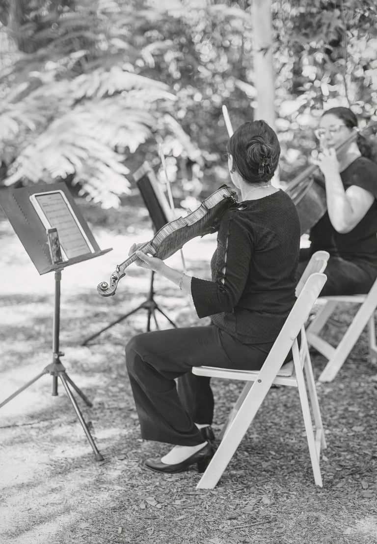 Violinist and Cellist perform at outdoor ceremony in a garden