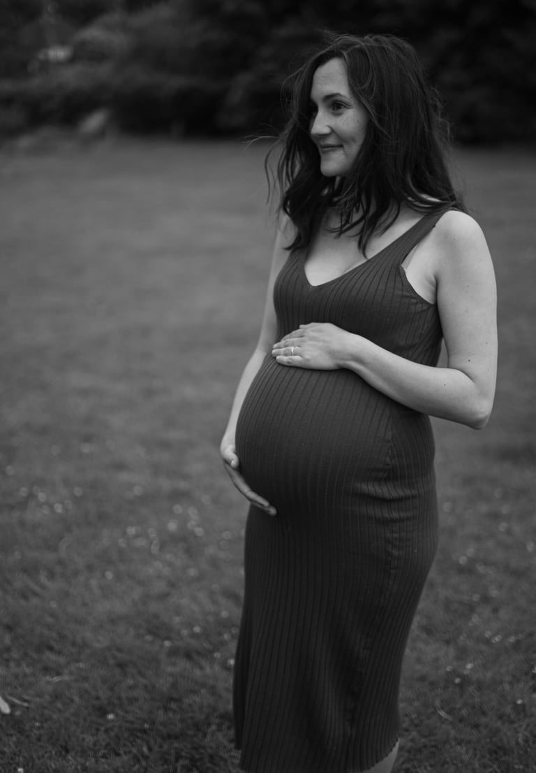 black and white image of pregnant woman holding her belly and smiling