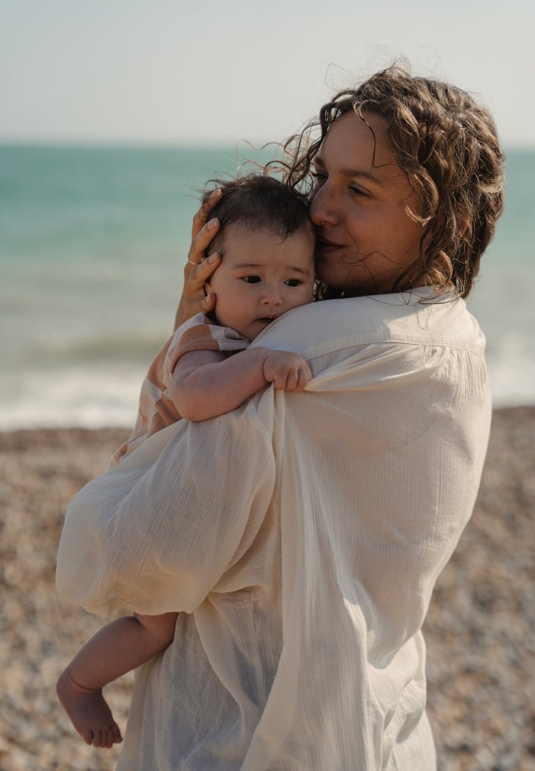 woman holding her baby by the sea