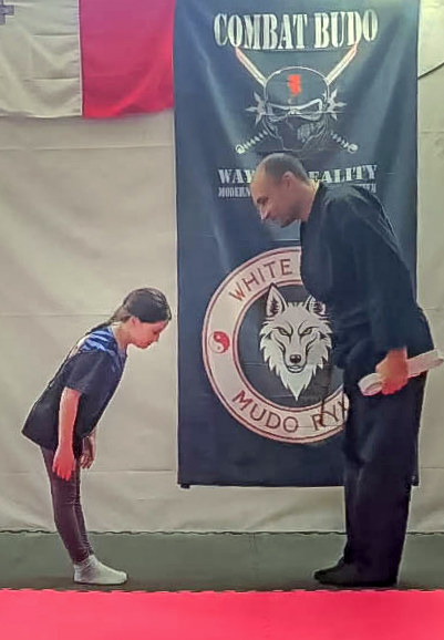 A martial arts student and instructor bowing in respect at a Combat Budo dojo.