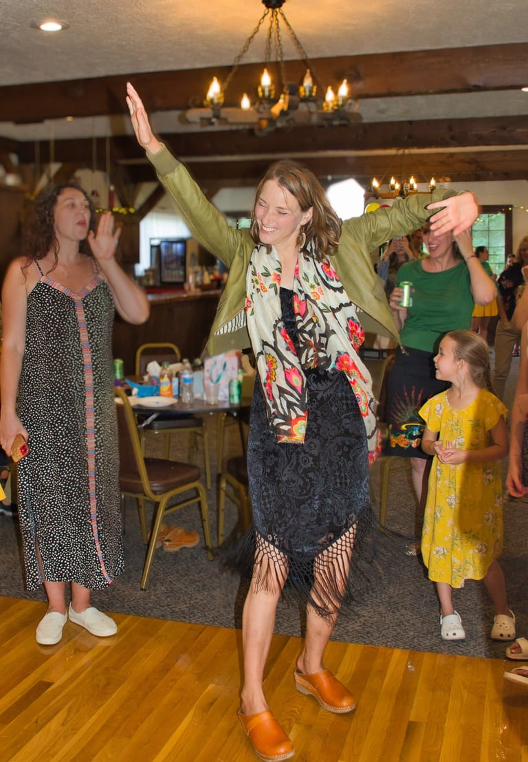 a woman in a black dress and green jacket dancing 