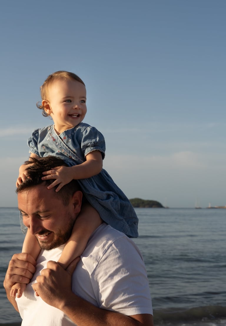 père tenant sa fille sur ses épaules a la plage 