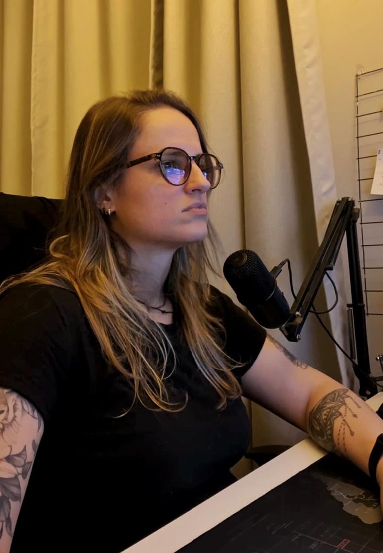 A woman with glasses and tattoos recording a podcast using a professional studio microphone.
