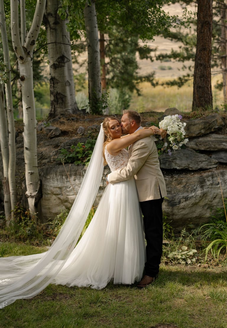 a bride and groom embracing each other in a forest