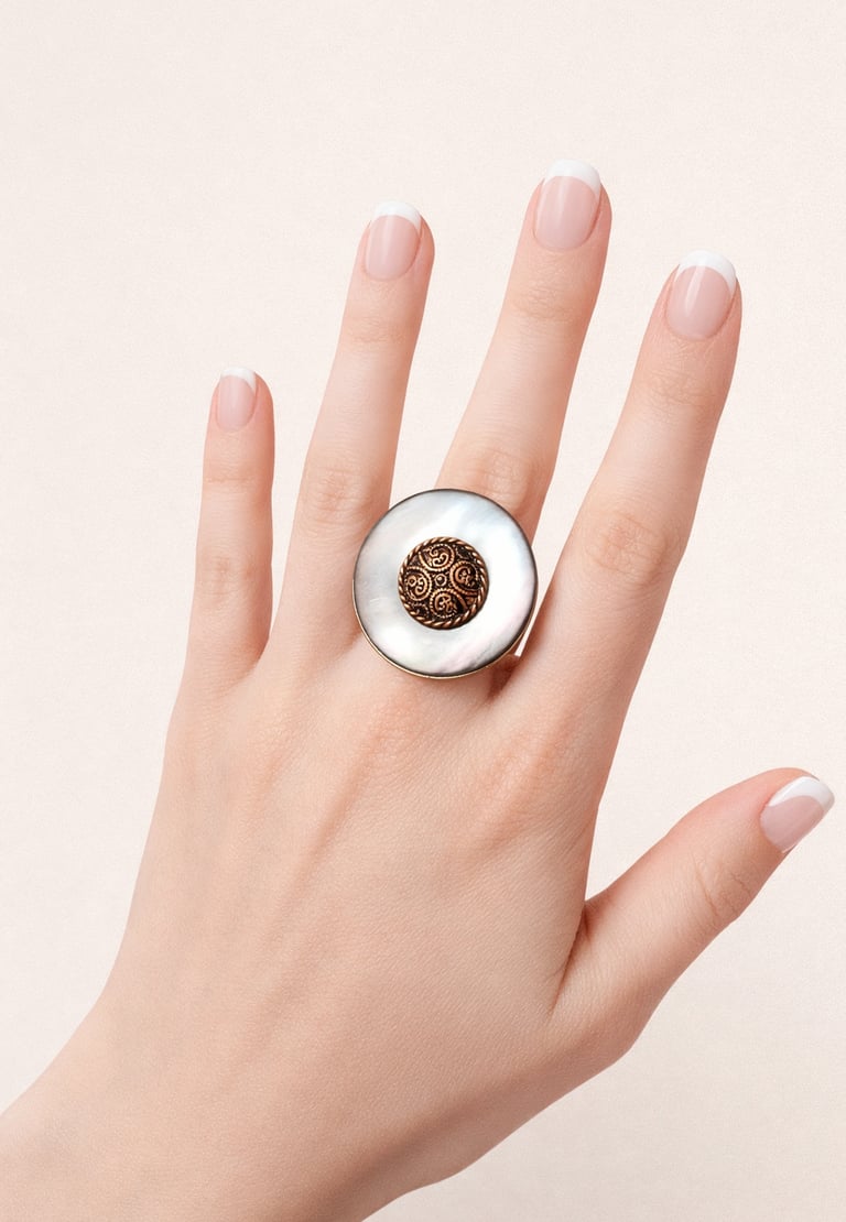 Vintage statement ring with large white mother of pearl and ornate bronze center on a hand.