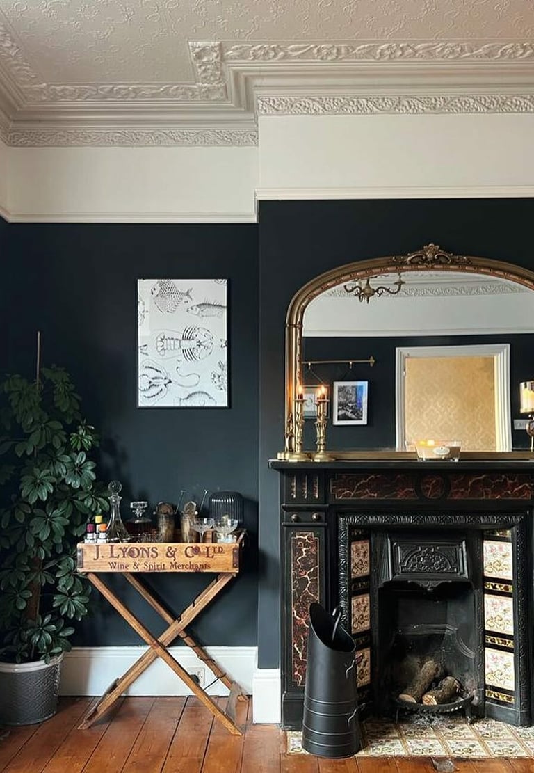 Elegant living room featuring a black marble fireplace, gold arched mirror, and dark charcoal walls.