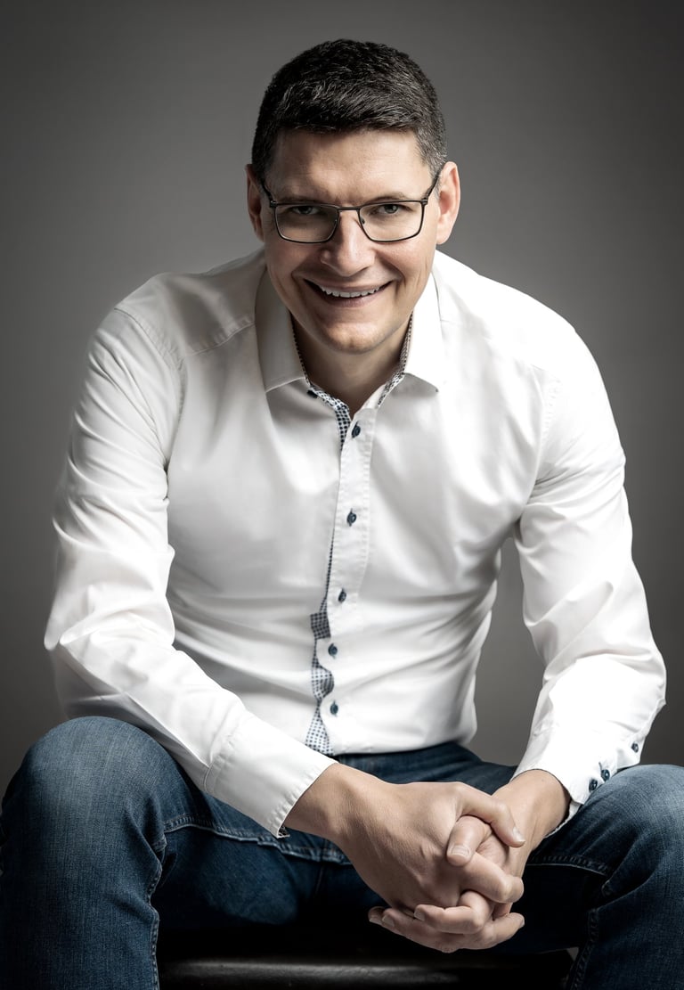 a corporate man in a white shirt and jeans sitting on a stool