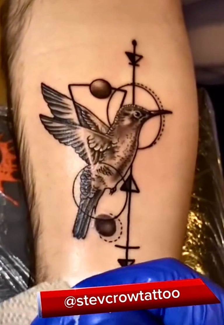 Detailed black and grey hummingbird tattoo with geometric shapes and lines on a forearm.