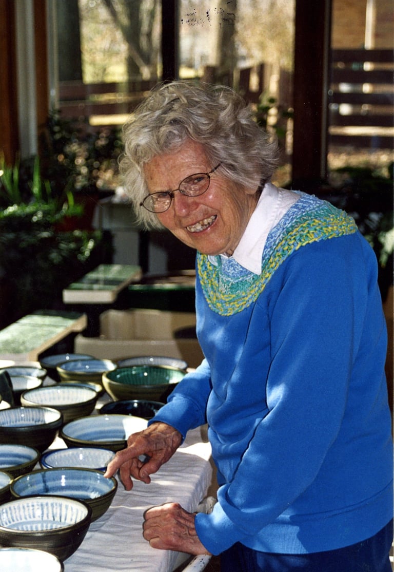 One of our founders, Naoma Powell, pictured with a table full of bowls she made.