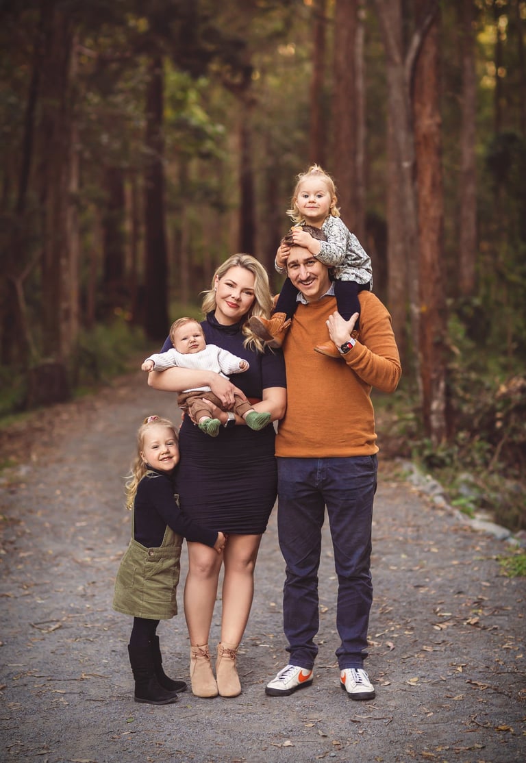 a family of three standing in a wooded area