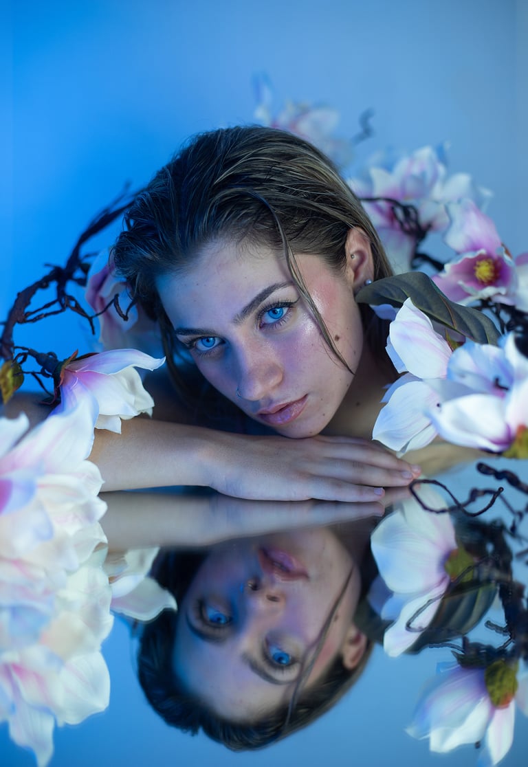 Modelo rubia con maquillaje de sirena, decorada con flores y gotitas de agua en estudio