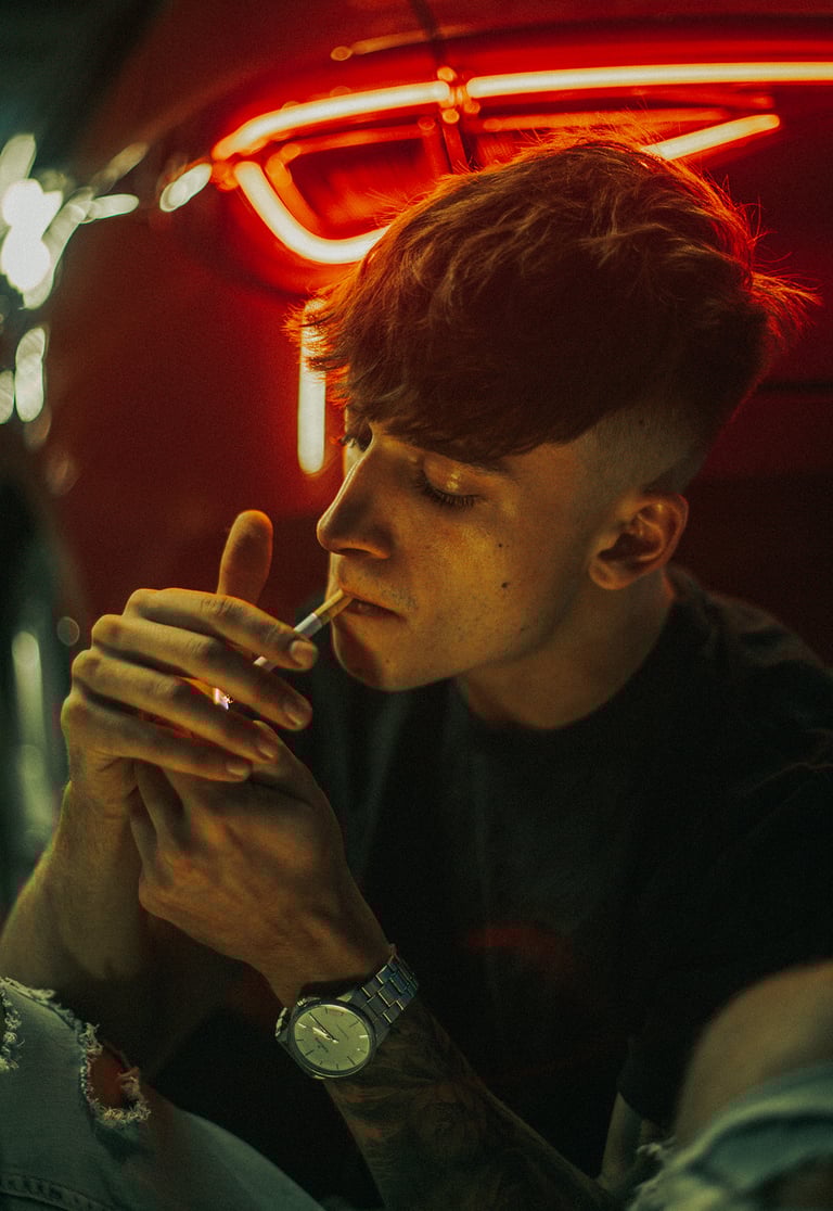 Fotografía artística de modelo fumando, destacando las luces rojas del coche
