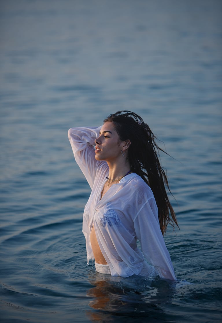 Sesión de fotos en la playa con modelo luciendo un vestido blanco y un collar llamativo