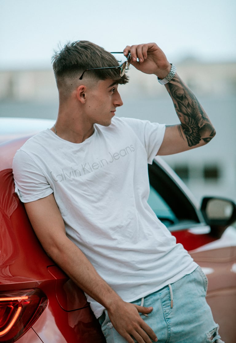 Plano abierto del modelo en una camiseta blanca Calvin Klein y un Seat León rojo