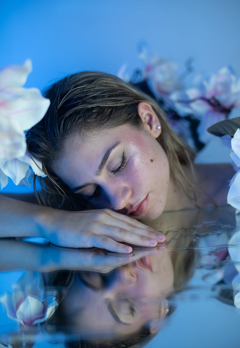 Primer plano de modelo rubia con maquillaje de sirena y reflejo de agua en espejo