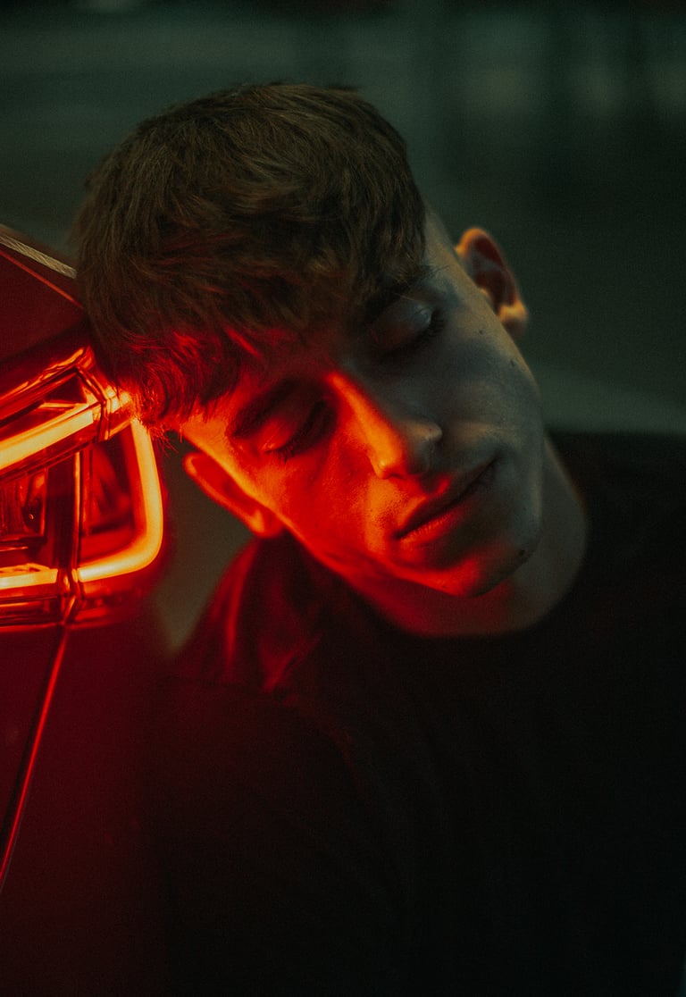 Escena en un parking oscuro con modelo y coche Seat León iluminado en rojo