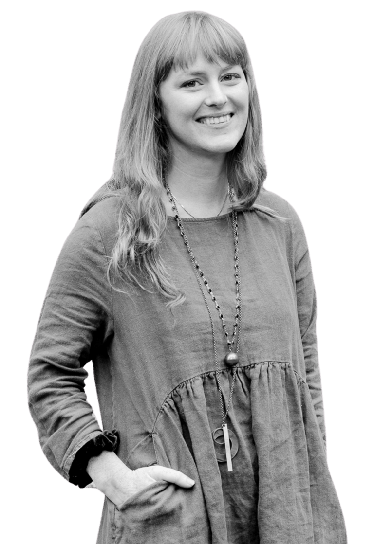 A picture of a woman standing. She is smiling.