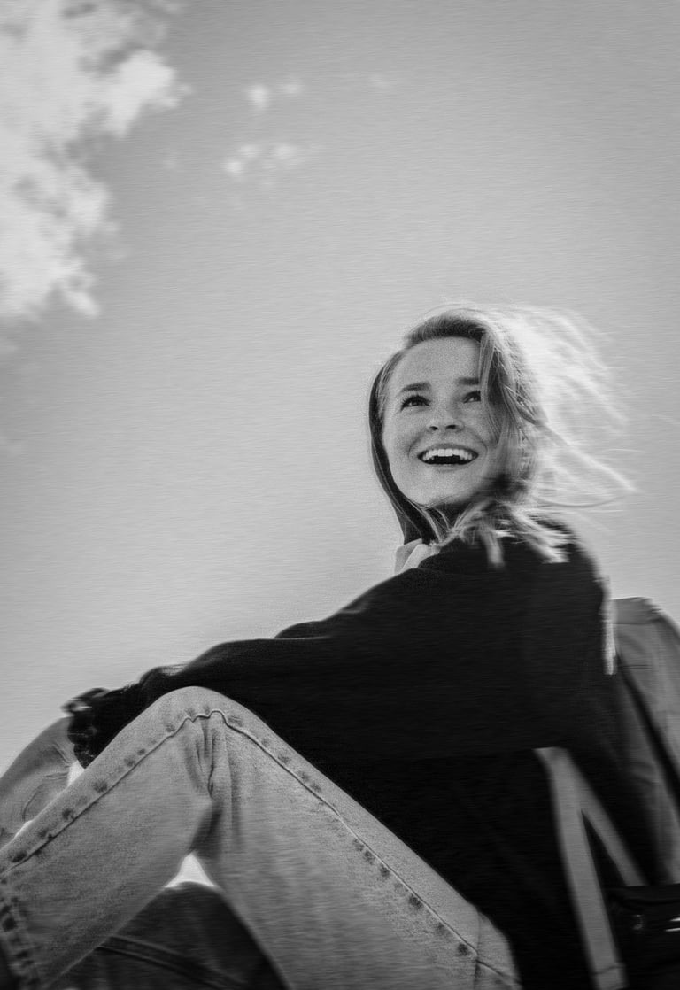 black and white photo of a young explorer woman sitting outdoors and smiling