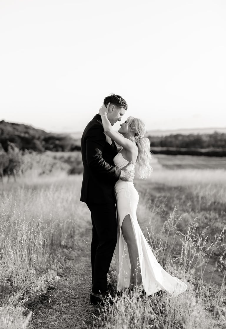 a bride and groom kissing in a field