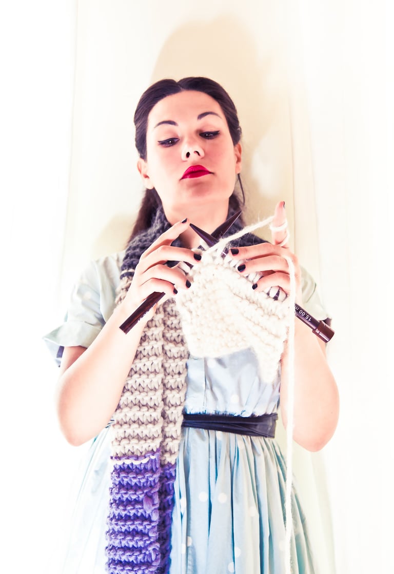 A woman knitting a long scarf.