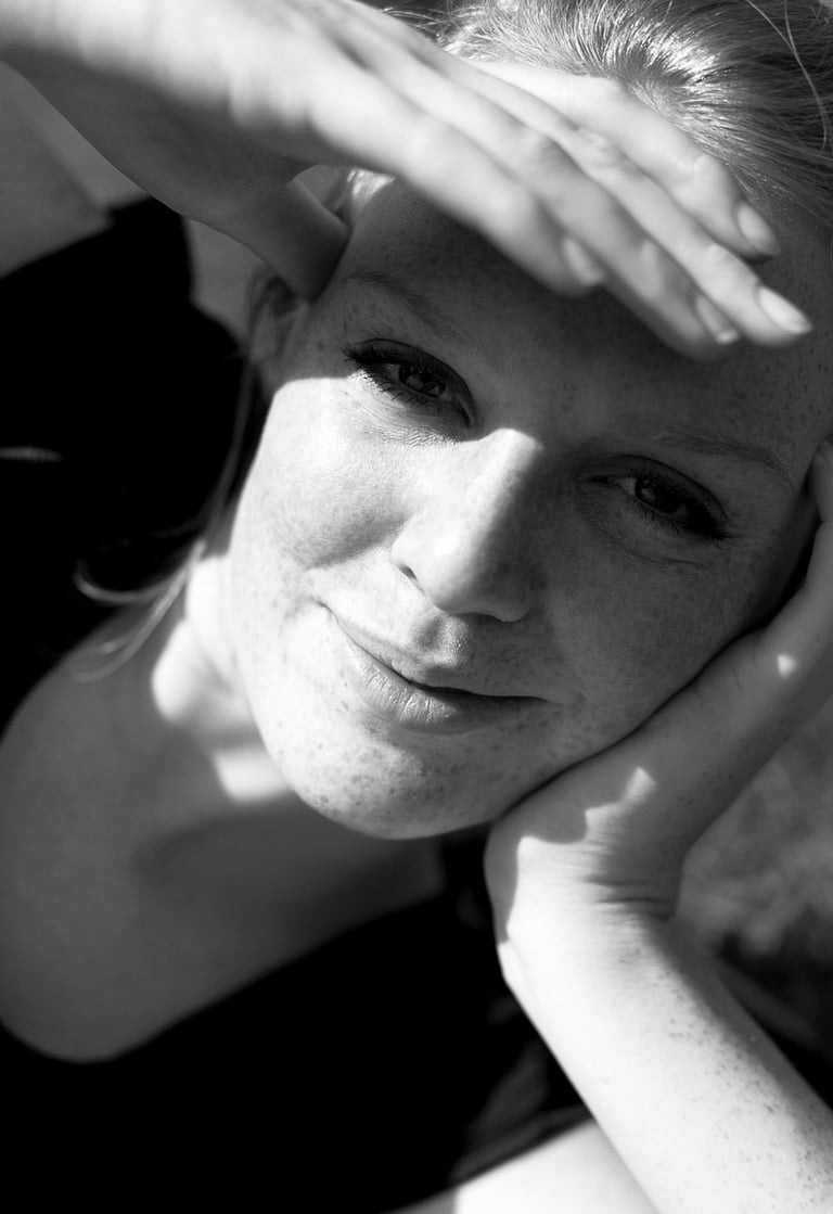 A woman lying down protecting her eyes from the sun.