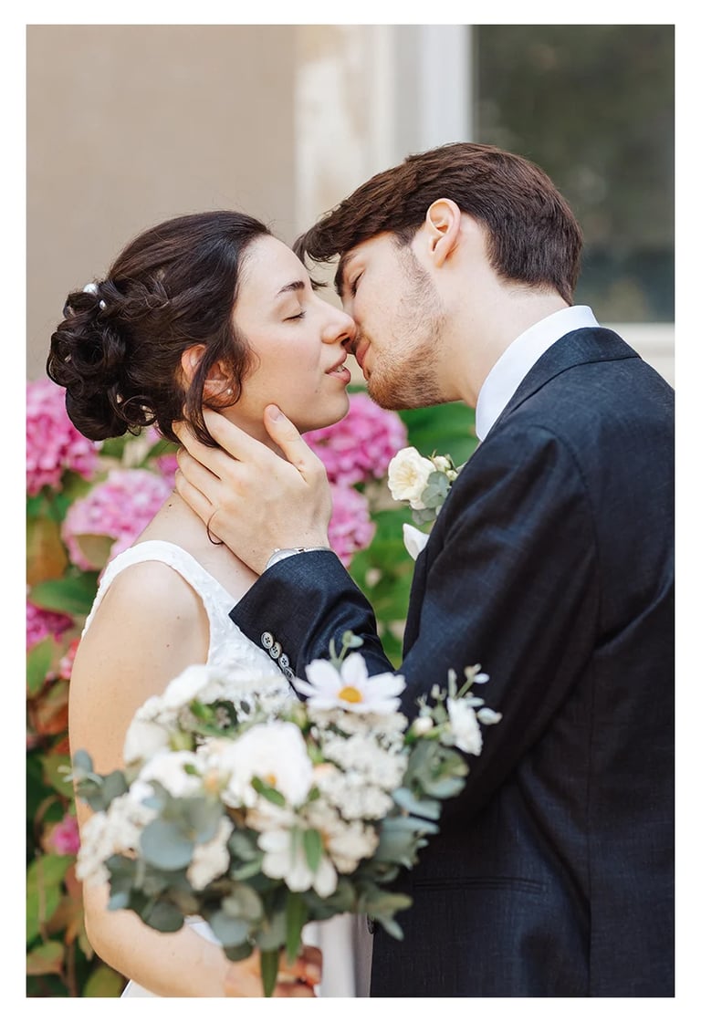Mariés s’embrassant tendrement devant des fleurs colorées, durant un mariage en Moselle. 