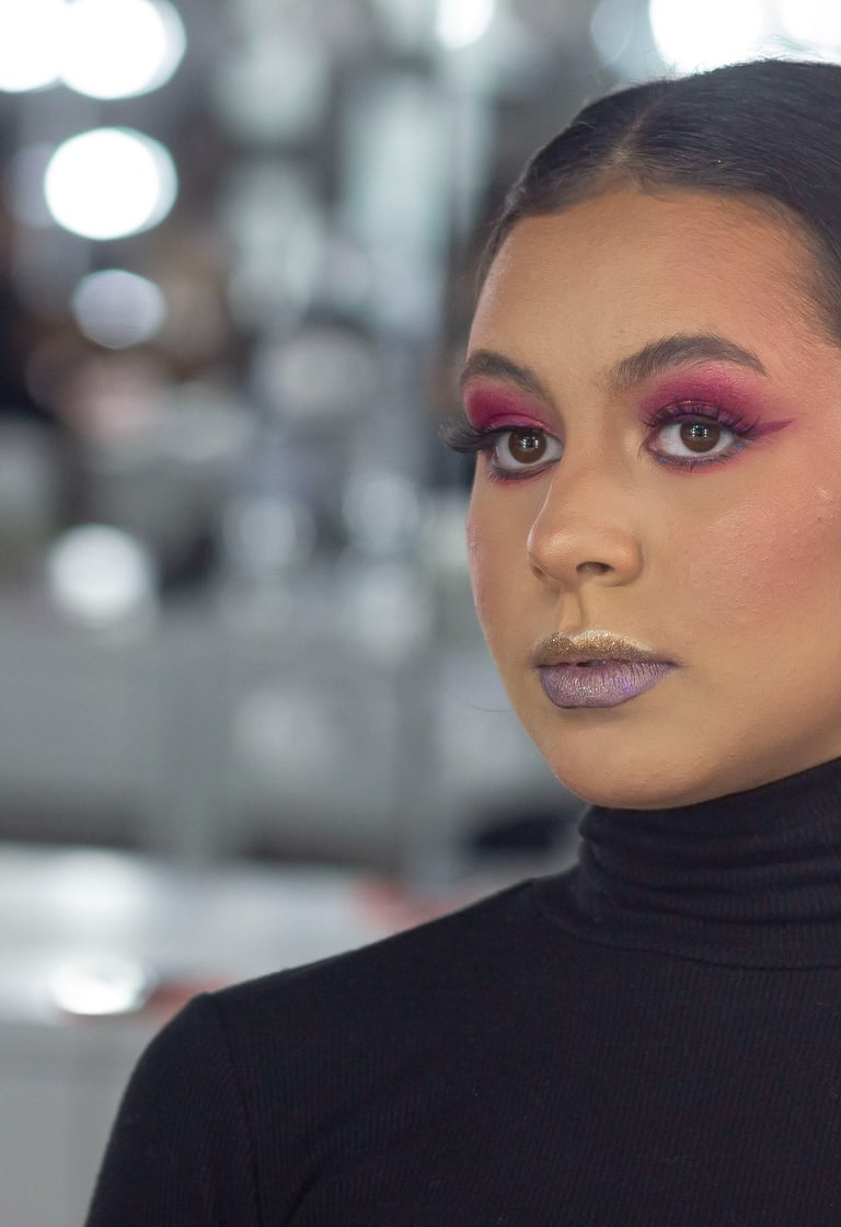 Una modelo que luce una atrevida sombra de ojos rosa y un lápiz labial brillante para lograr un look