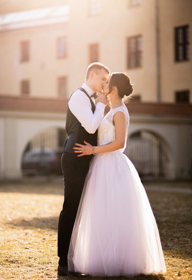 Jaunikis bučiuoja jaunąją golden hour spinduliuose