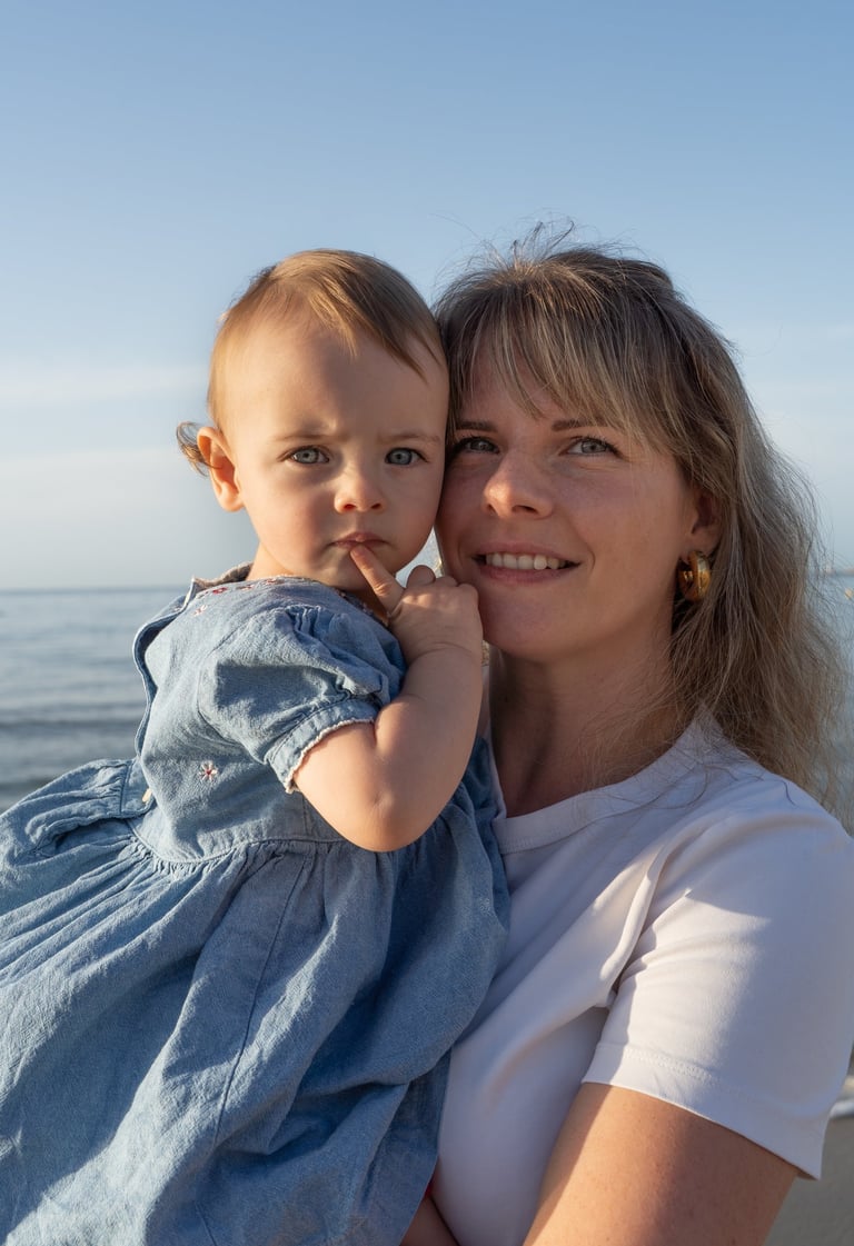mère tenant sa fille dans les bras sur la plage 