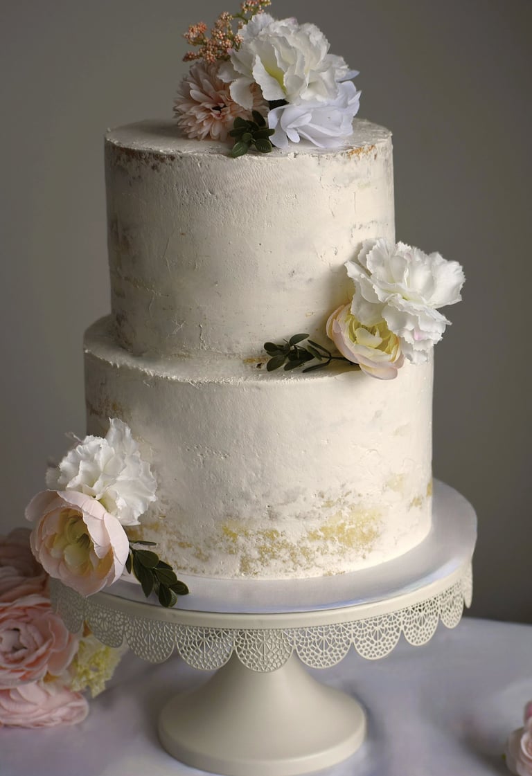 Elegant two-tier white semi-naked wedding cake decorated with flowers Chicagoland weddings