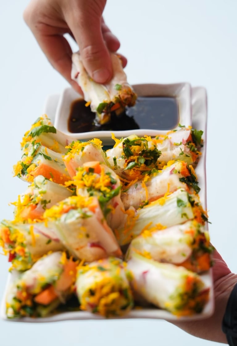 a person holding a plate with food and dipping sauce